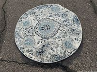 Round area rug placed outdoors showing pattern and color details.