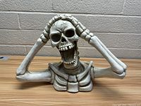 Front view of the skeleton Halloween decoration showing the head, arms raised to the head, and upper chest bones.