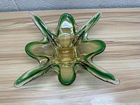 Top view of the green glass dish showing petal-like extensions and translucent body.