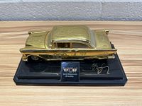 Front and side angle of the gold WCW branded model car on black base with plaque and signature