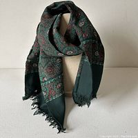 Full view of the green patterned Devilin's English Shop scarf with fringe ends displayed on a mannequin.