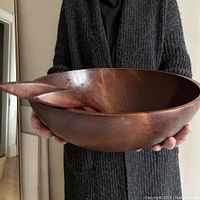 Person holding the large wooden salad bowl and servers, showing scale and finish