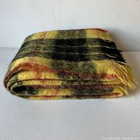 Folded mohair and wool throw with yellow, black, and red check pattern.