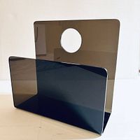 Front angled photo of smoked lucite record/magazine stand showing tall back panel with large circular cutout and front panel slot.