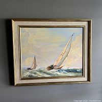Frontal view of the framed oil painting showing two sailboats in choppy sea with cloudy sky in pastel tones.