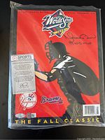 Front cover of the 1999 Official World Series program featuring a catcher silhouette on red background, signature and inscription, plus Sports Memorabilia COA sticker.