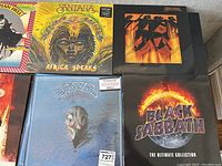 Six vinyl LPs laid out on grey upholstery showing Santana, Black Sabbath, Jethro Tull and two Kiss albums