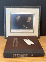 Framed signed photograph of George Gershwin at piano alongside Ira Gershwin lyrics book on table
