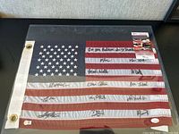 American flag laid flat in protective sleeve showing 50-star canton and 13 stripes with multiple signatures