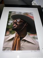 Frontal view of matted and framed color photograph of Stevie Wonder wearing hat and sunglasses