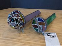 Both stained glass kaleidoscopes side by side on bamboo surface