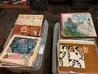 Two plastic tubs filled with record albums, tubs stacked side by side
