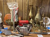 Front view showing brass and silver plated items along with wood plaques and wrapped candles.