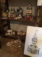 Six ceramic Christmas village houses by Department 56 displayed on shelves, showing different roof styles, window designs, and snow details with electrical cords below