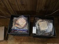 Two crates filled with plates in plastic bags and their certificates of authenticity, stacked for sale.