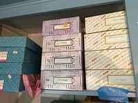 Stack of boxed dolls from Effanbee International and Madame Alexander showing multiple series names and international themes on box sides.
