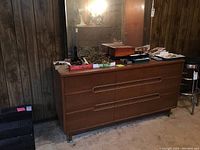 Front view of dresser with mirror in background and assorted items on top