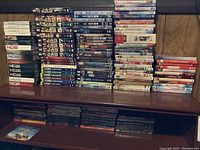 Two shelves filled with DVDs, including TV shows and holiday movies stacked upright and some laying flat in shelf compartments.