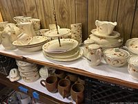 Overview of shelves displaying plates, bowls, cups, canisters and two-tier stand