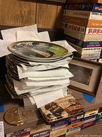 Stack of over 15 Franklin Mint John Wayne plates with protective paper between, medallion, and playing cards box with vintage John Wayne design