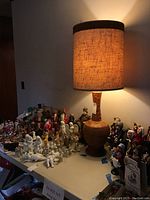 Full view of the lamp lit on a table with various figurines around it.