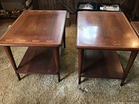 Pair of side tables front view on carpet showing overall shape and lower shelf