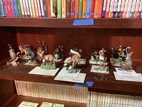 Twelve Lenox Woodland Animals sculptures displayed on shelf with some COA cards visible.