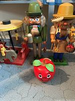 Wide shot showing two large wooden nutcrackers, wooden carousel toy with animals, and Fisher Price apple toy on carpet