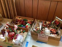 Three cardboard boxes on a table holding mixed glass ornaments