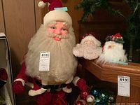 Full front view of the 36-inch Playshop Santa in red velvet suit with two vintage Santa heads on a wooden table to the right.