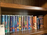 Shelf of Disney classic VHS movies with spines visible, colorful art illustrating each title, including The Rescuers, Robin Hood, Peter Pan, and more.