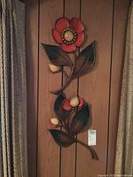 Two vintage plastic wall art panels showing red and cream flowers with green leaves against wood paneling background