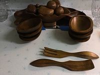 Overview of wooden bowls stacked with two serving utensils placed in front.