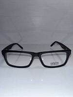 Front angled view of black rectangular eyeglass frames with clear lenses on a white surface.