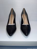 Front view of the black leather pointed-toe high heel shoes showing shape and material.