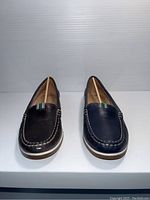Front view of Naturalizer women's loafers size 6 showing black and navy leather slip-on shoes with white stitching and striped fabric accents on tongue area.
