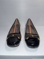 Front view showing black patent toe with gold accents and bow detail