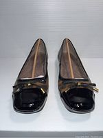 Front view of the pair of black patent toe, bow decorated, snakeskin patterned Naturalizer ladies flats, size 8.5W