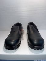 Front view of the pair of black slip-on safety shoes showing toe and top surface.