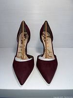 Front view of pair of pointed toe high heel shoes in burgundy color, showing shape, material, and toe design.