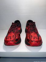 Front view of the pair of Saucony men's running shoes showing red and black color with speckled design and laces.