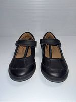 Front view of the black Mary Jane style kids shoes showing Velcro straps and stitching detail