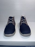 Front view of pair of UGG kids shoes, navy blue and grey with laces, showing clean and new condition.