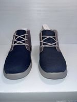 Front view of the navy and gray UGG kids shoes, showing laces and shoe shape.