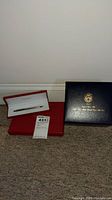 Red Cartier case open with pen inside and closed black stationery box to the right