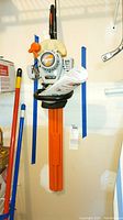Full view of Echo HC150 gas hedge trimmer hanging on wall with orange blade cover and manual attached to handle.