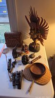 Full view of lot showing large winged wooden figurine, smaller wooden figurines, wooden bowl, fan, small carvings, and basket