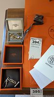 Overview of Hermès boxes containing cufflinks, studs and chain key fob, with ribbon and seller receipt visible