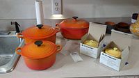 All three orange pots and two boxed yellow mini cocottes on countertop
