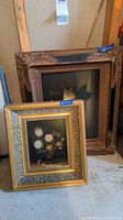 Two paintings stacked, front floral and rear fruit still life, showing ornate frames